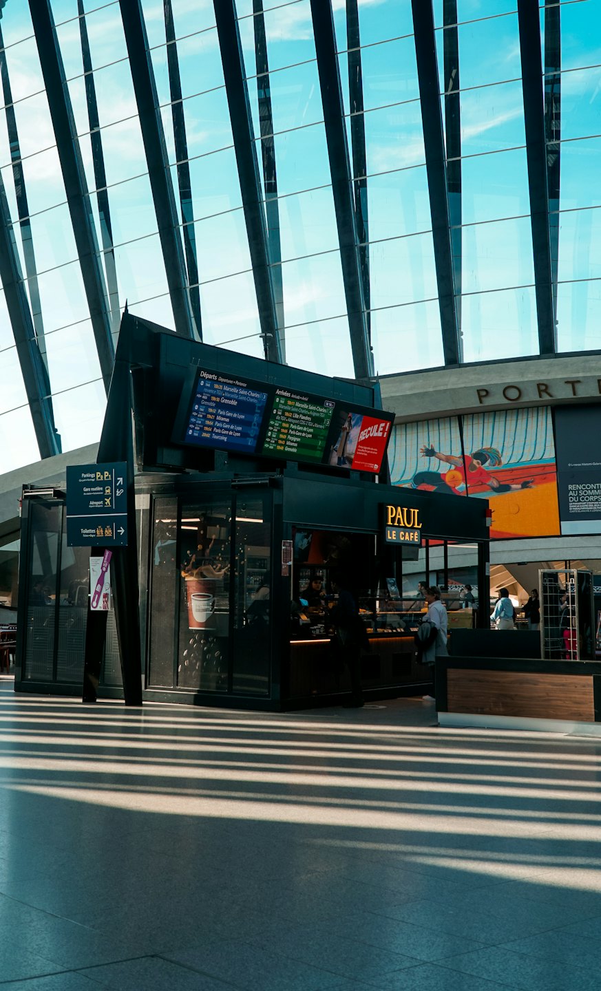 Pendlande människor går förbi en Paul Le Café-kiosk inne på en station.